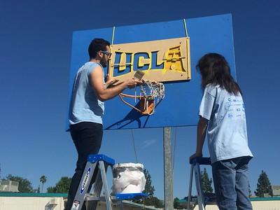 UCLA volunteers painting UCLA on basketball backdrop