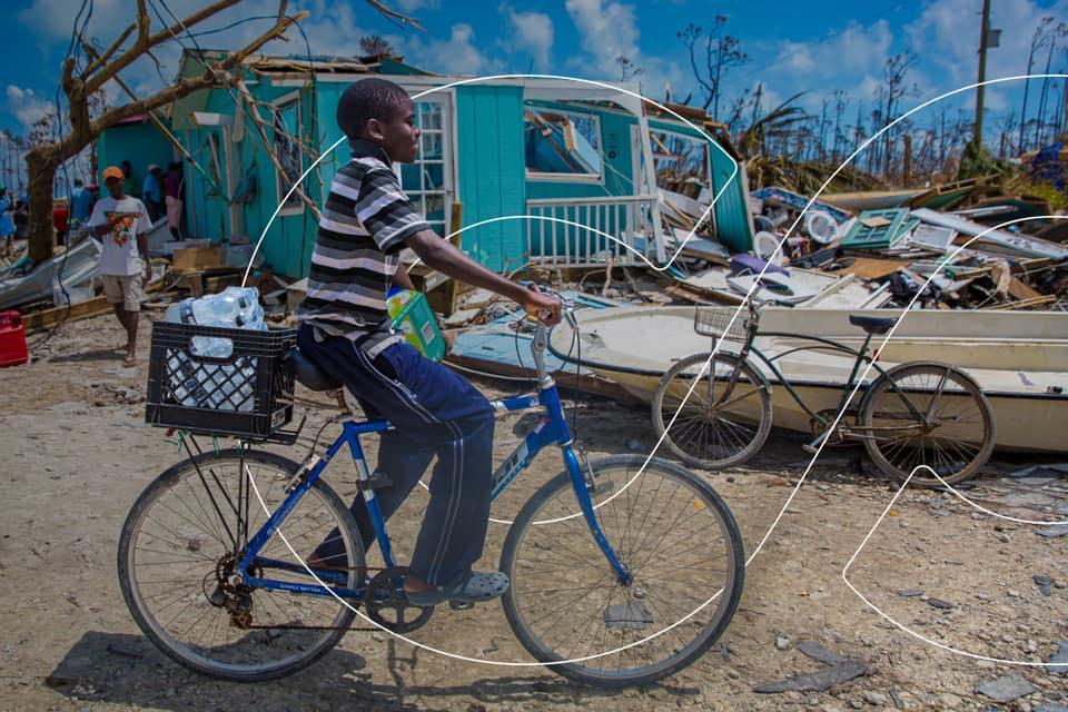 This is an image of a boy riding his bicycle in the aftermath of an environmental crisis. This image captures the kind of environment this organization helps to serve. 