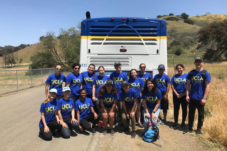 Volunteer Group posing in front of a UCLA Bus