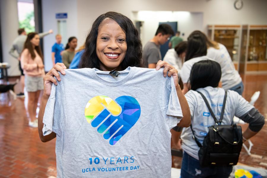 This is a photo of a UCLA volunteer holding up a Volunteer Day t-shirt.